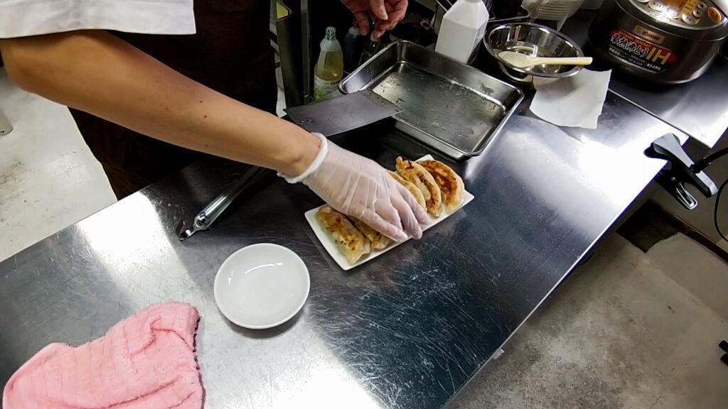 焼きたて餃子を並べる職人